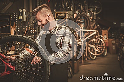 Stylish bicycle mechanic doing his professional work in workshop. Stock Photo