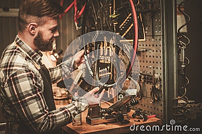 Stylish bicycle mechanic doing his professional work in workshop. Stock Photo