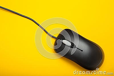 Stylish black optical computer mouse isolated on a yellow background. View from above Stock Photo