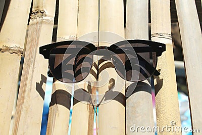 Stylish black sunglasses on bamboo background, elegant eyeglasses accessory isolated on wooden surface Stock Photo