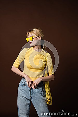 stylish blonde girl with string bag wearing yellow sunglasses and looking away Stock Photo