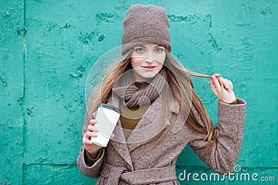 Stylish blonde woman in trendy urban outwear posing cold weather against grunge metal green painted background. Stock Photo