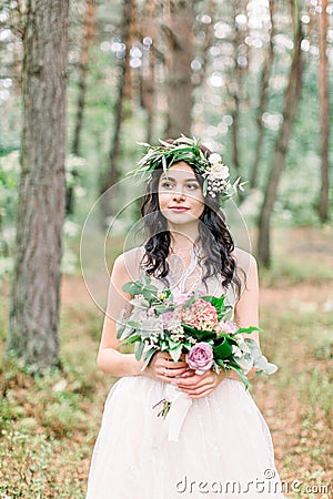 Stylish bride posing with bouquet on background of forest, luxury gorgeous boho wedding at forest outdoors Stock Photo