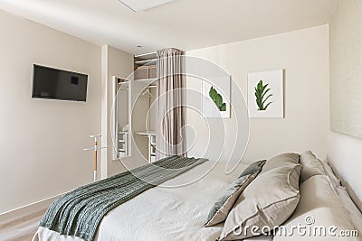 Stylish bright bedroom with a TV and a double bed and an empty wardrobe for things with beige wallpaper and cute Stock Photo