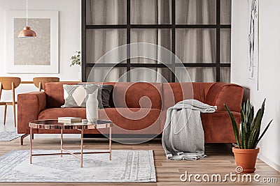 Stylish brown corner sofa with patterned pillows in elegant living room interior with mullions wall Stock Photo