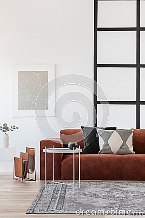 Stylish brown corner sofa with patterned pillows in elegant living room interior with mullions wall Stock Photo