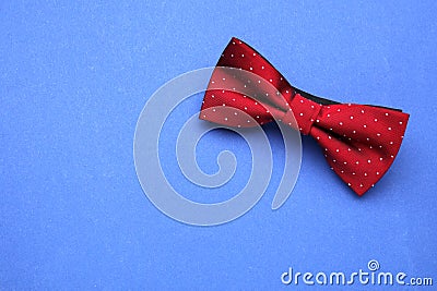 Stylish burgundy bow tie with polka dot pattern on blue background, top view. Space for text Stock Photo