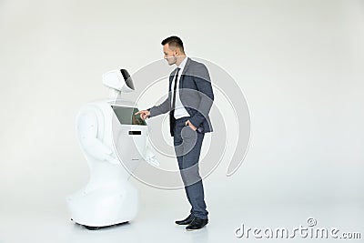 A stylish businessman communicates with a robot. Cybernetic system today. Modern Robotic Technologies. Humanoid Stock Photo