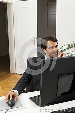 Stylish businessman in a suit sitting at his desk Stock Photo