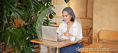 Stylish businesswoman with laptop, sitting in cafe and working on computer, managing business and drinking coffee Stock Photo