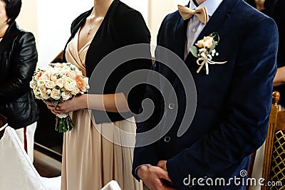 Stylish chauffeur and bridesmaid holding bouquet at wedding ceremony at church Stock Photo