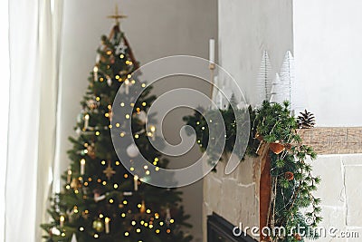 Stylish christmas living room with modern decorated christmas tree with vintage baubles and scandinavian decor on fireplace mantel Stock Photo