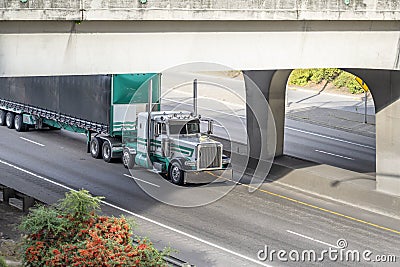 Stylish classic American white and green semi truck tractor transporting cargo in black covered semi trailer with front wall Stock Photo