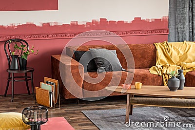 Stylish coffee table in front of brown velvet corner sofa in living room with ombre wall Stock Photo