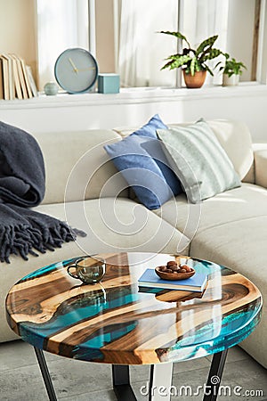 Stylish composition with design epoxy coffee table, sofa, blanket, pillows, book, decoration and personal accessories. Stock Photo