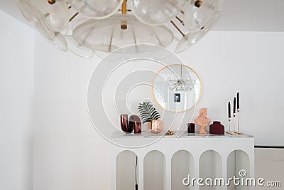 Stylish composition of red mirror table lamp with gold stationary on white marble top with copy space on white wall background / Editorial Stock Photo