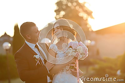 Stylish couple of happy newlyweds posing in the park on their wedding day. Perfect couple bride, groom funny joke Stock Photo