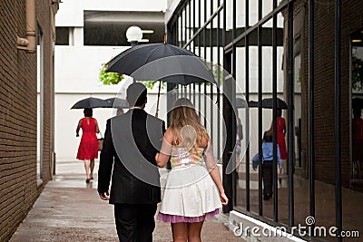 Stylish couple walking in rain in modern alley under one umbrella Editorial Stock Photo