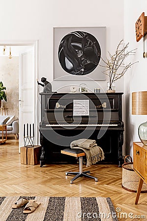 Stylish and cozy interior of living room with black piano, furniture, plant, wooden clock, lamp, mock up painitngs, carpet. Stock Photo