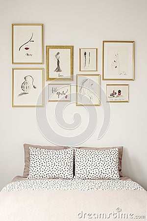 Stylish drawings gallery in golden frames above a cozy double be Stock Photo