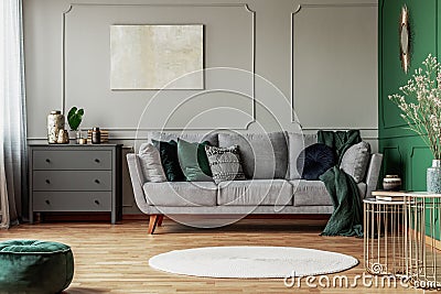 Stylish emerald green and grey living room interior design with abstract painting on the wall Stock Photo