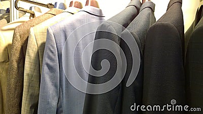Stylish expensive men`s business suits for sale. Clothes on hangers. Fashion for managers and businessmen concept. Premium store. Stock Photo