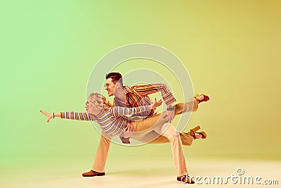 Stylish, expressive, talented young man and woman in vintage clothes dancing against gradient green yellow background Stock Photo