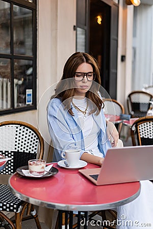 Stylish freelancer using laptop near dessert Stock Photo