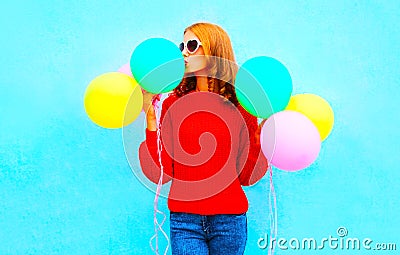 Stylish funny girl kisses an air colorful balloons on a blue Stock Photo