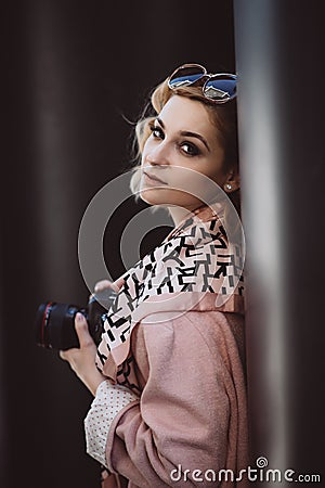 Stylish girl blonde photographer in pink clothes and sunglasses with a camera in her hands posing in the city Stock Photo