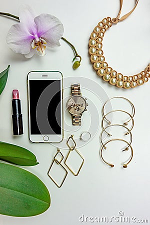 Stylish girly set of accessories watch necklace earrings bracelets lipstick with orchid on a white background Stock Photo