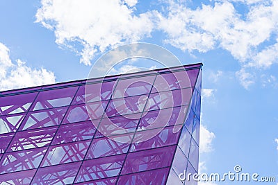 Stylish Glass Facade of Violet Tinted Semi-Transparent Glass Building Against Blue Sky with Sunbeams Editorial Stock Photo