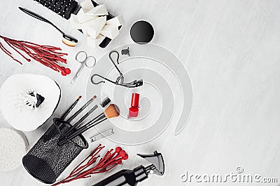 Stylish glossy black cosmetic products and mackup accessories with red twig and nail polish on soft light white wooden background. Stock Photo