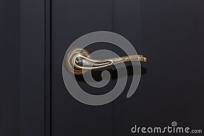 Stylish gold handle on a black door. Modern trends in interior design. Close-up Stock Photo