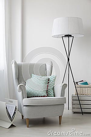Stylish grey armchair and a floor standing lamp Stock Photo