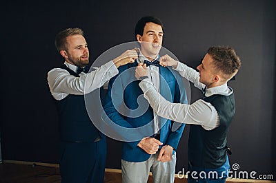 Stylish groomsmen helping happy groom getting ready in the morni Stock Photo