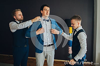 Stylish groomsmen helping happy groom getting ready in the morni Stock Photo