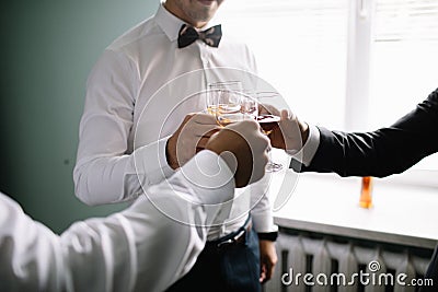 Stylish groomsmen helping happy groom getting ready in the morning Stock Photo
