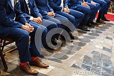Stylish groomsmen sit during the ceremony in the church Stock Photo