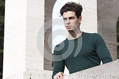 Stylish hair young man outdoors on the ledge, tight knit Stock Photo