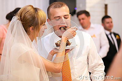 stylish happy bride and groom cutting and tasting fabulous wedding cake in a restaurant Stock Photo