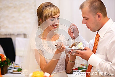 stylish happy bride and groom cutting and tasting fabulous wedding cake in a restaurant Stock Photo