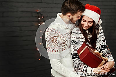 Stylish happy couple with big red present smiling gently hugging Stock Photo