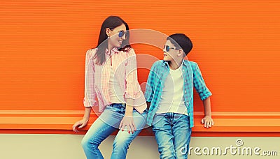 Stylish happy smiling mother with son teenager look at each other posing together in sunglasses, checkered shirts, jeans in the Stock Photo
