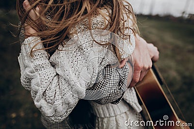 stylish hipster couple embracing in windy field. boho gypsy woman and man with guitar strongly hugging. atmospheric motion moment Stock Photo