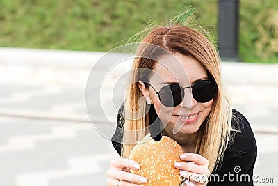 Stylish hipster woman eating a juicy burger Stock Photo