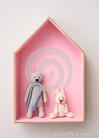 Stylish house shaped shelf with toys on white wall. Baby room interior design Stock Photo