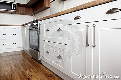Stylish light gray handles on cabinets close-up, kitchen interior with modern furniture and stainless steel appliances. kitchen d Stock Photo