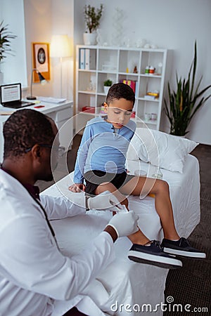 Stylish little boy visiting pediatrician after falling from bike Stock Photo