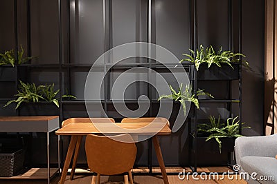 Stylish loft working corner with wood table, leather chair and artificial plant with black metal rod on the background / interior Stock Photo